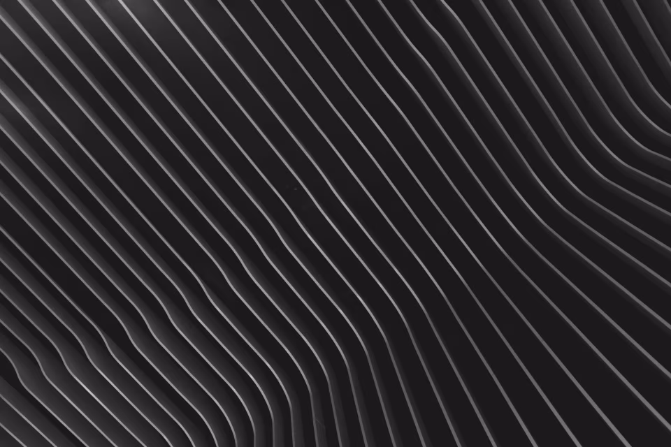 Schwarz-weiße Nahaufnahme von gebogenen, parallelen Linien mit Schatten und Lichtreflexen