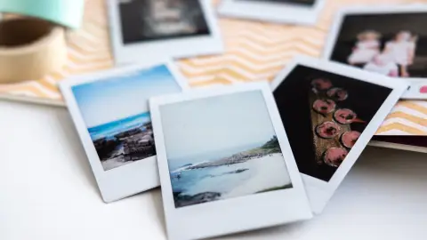 Mehrere Polaroid-Urlaubsfotos liegen auf dem Rücken eines Fotoalbums