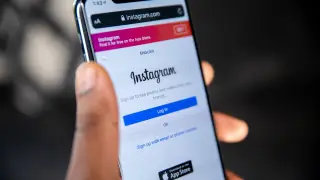 Eine Hand hält ein Smartphone, auf dem das Log-In-Formular von Instagram im Browser geöffnet ist