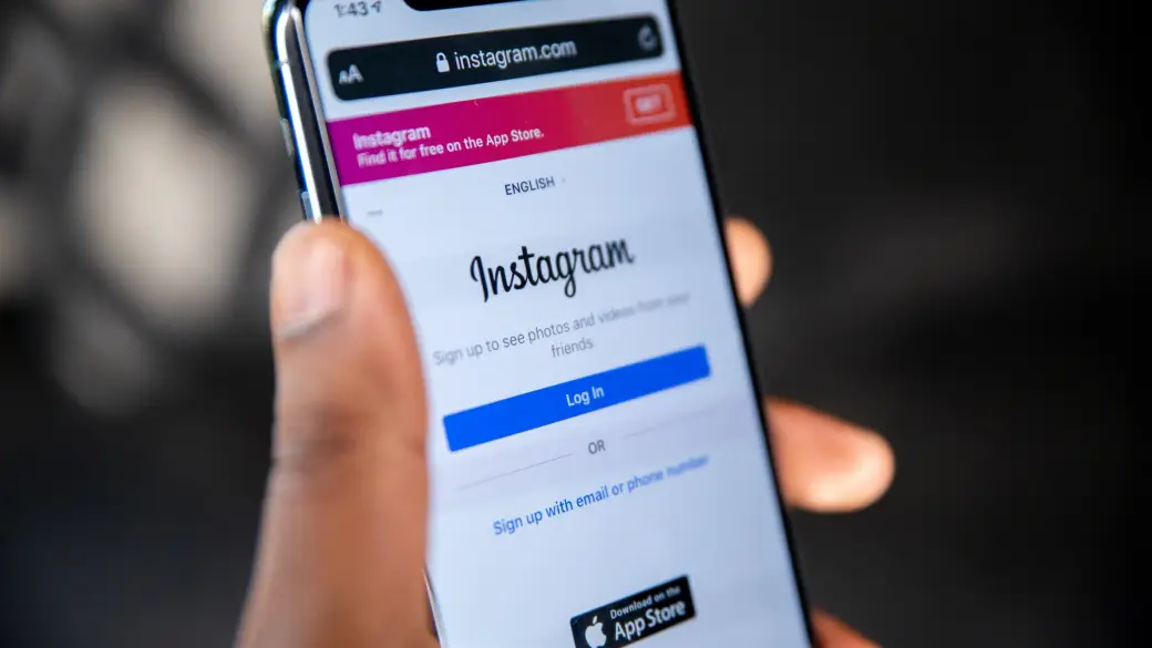 Eine Hand hält ein Smartphone, auf dem das Log-In-Formular von Instagram im Browser geöffnet ist