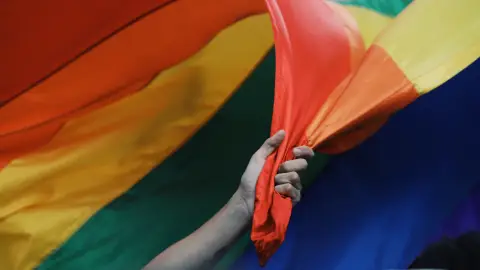 eine Hand hält eine Regenbogenflagge fest